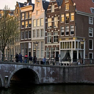Netherlands, Amsterdam. Traditional houses along the canals and bridge crossing
