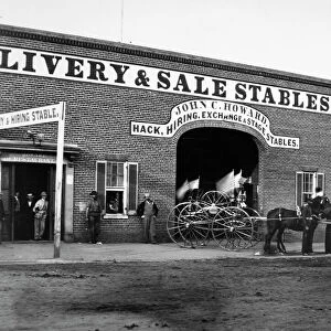 John C. Howards livery stable and saloon on G Street in Washington, D. C. where John H. Surratt, a conspirator in the Abraham Lincoln assassination, kept horses before leaving town on 1 April 1865. At right is a horse drawn hose reel belonging to the Northern Liberties Fire Company. Photographed in 1865
