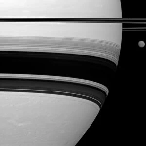 Saturns largest moon, Titan, looks small here, pictured to the right of the gas giant in