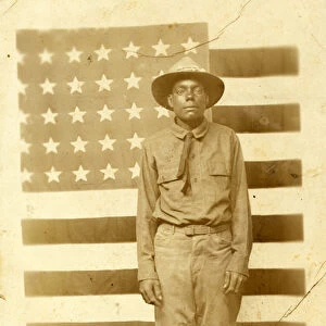World War I soldier with American flag in background, 1914-18 (b / w photo)