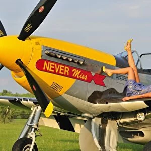 1940s style pin-up girl lying on the wing of a P-51 Mustang