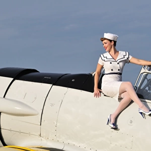 1940s style pin-up girl sitting outside the cockpit of a T-6 Texan