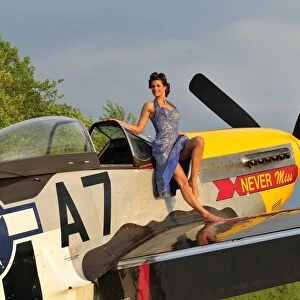 1940s style pin-up girl standing barefoot on the wing of a P-51 Mustang