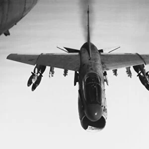 An A-7 Corsair II flies toward targets in Vietnam, armed with bomb clusters, 1969