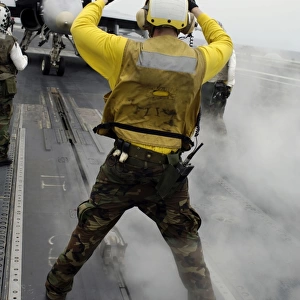 An aircraft director signals a F / A-18C Hornet on the flight deck of USS Kitty Hawk
