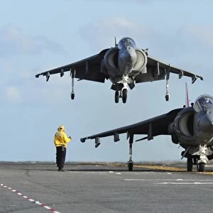 An AV-8B Harrier prepares for takeoff as another lands aboard USS Makin Island