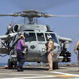 Aviation Boatswainas Mates run to refuel an MH-60S Sea Hawk helicopter