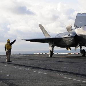 Aviation Boatswains Mate signals the pilot to lift an F-35B Lightning II off the