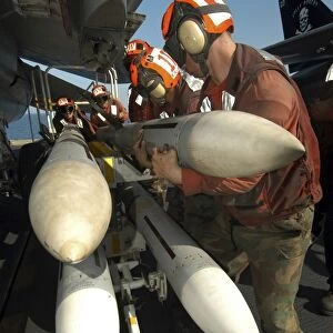 Aviation Ordnancemen load AIM-7 Sparrow air-to-air missiles on an F-14B Tomcat