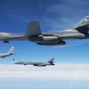 A B-1B Lancer stands by as another Lancer connects with a KC-135 Stratotanker
