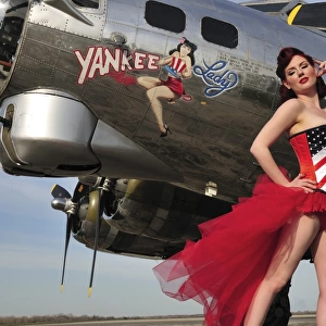 Beautiful 1940s style pin-up girl standing under a B-17 bomber