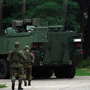 Belgian Infantry soldiers walk alongside the Piranha IIC armoured infantry vehicle
