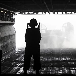 Boatswains Mate directs a landing craft air cushion as it approaches USS Kearsarge