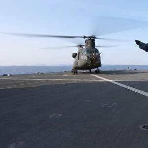 Boatswains Mate signals to an Army CH-47 Chinook helicopter