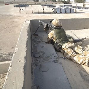 A British soldier provides security from a rooftop in Basra, Iraq