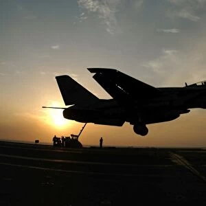 An F-14D Tomcat makes an arrested landing as the sun sets