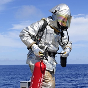 Firefighter carries a CO2 fire extinguisher onto the flight deck of USS Denver
