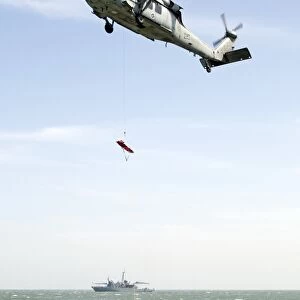 A litter is lowered from a SH-60B helicopter during a medical evacuation