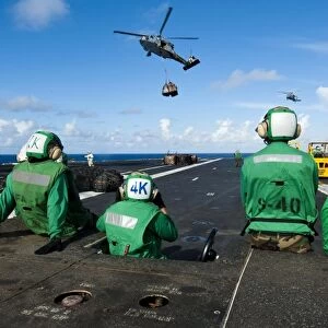 Logistics specialists stand by as an MH-60S Sea Hawk delivers supplies
