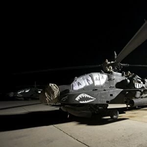 Maintenance crew work on an AH-64D Apache Longbow at night