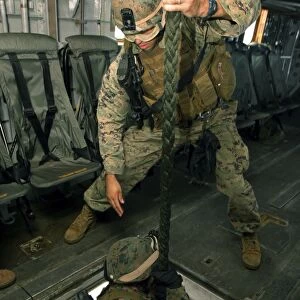 A Marine sends a fellow Marine down the hell hole of a CH-53E Super Stallion