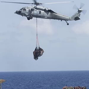 An MH-60S Sea Hawk picks up cargo from USNS Medgar Evers