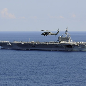 An MH-60S Seahawk helicopter flies over USS George H. W. Bush