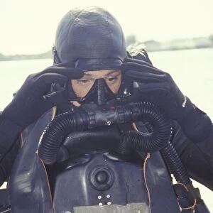 A Navy SEAL combat swimmer adjusts his dive mask