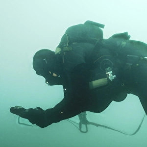 A Navy SEAL combat swimmer navigates the water utilizing a compass board