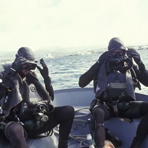 Navy SEALs combat swimmers donn their equipment in a utility boat