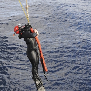 An Operations Specialist is lifted out of the ocean