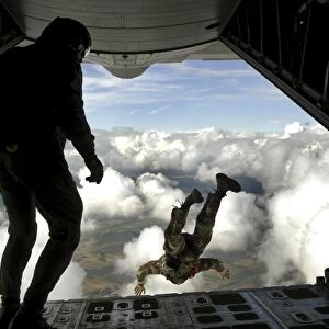 Pararescuemen jump out the back of a C-130 Hercules