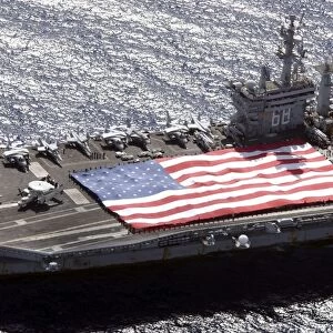 Personnel participate in a flag unfurling rehearsal on the flight deck aboard USS Nimitz
