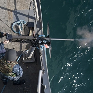 A sailor fires a. 50-caliber machine gun aboard USS New Orleans