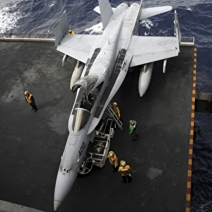 Sailors move an F / A-18C Hornet into the hangar bay