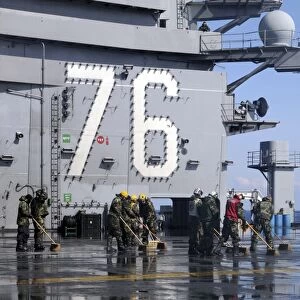 Sailors scrub the flight deck aboard the aircraft carrier USS Ronald Reagan