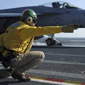 A shooter signals the launch of an F / A-18 Super Hornet