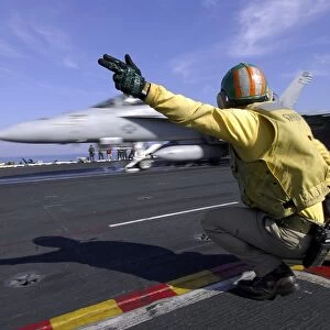 A shooter signals the launch of an F / A-18 Super Hornet