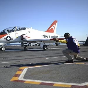 Shooter signals to the pilot of a T-45C Goshawk training aircraft