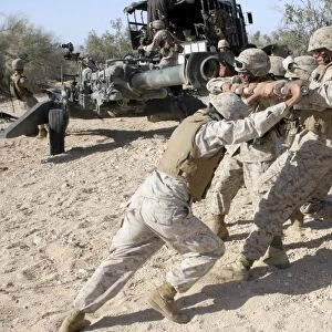 Soldiers move the muzzle-end of a M777 Lightweight Howitzer