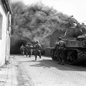 Soldiers move through a smoke filled street, Wernberg, Germany