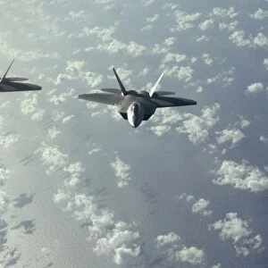 A three-ship formation of F-22 Raptors fly over the Pacific Ocean