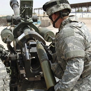 U. S. Army Soldier loads a 105mm artillery round into a M119 Howitzer