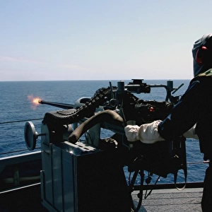 U. S. Navy Gunners Mate fires a Mark 38 (MK-38) 25 mm machine gun system