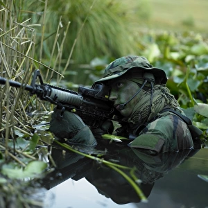 U. S. Navy SEAL crosses through a stream during combat operations