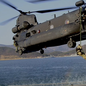 A U. S. Navy SEAL fast-ropes from a MH-47 Chinook helicopter
