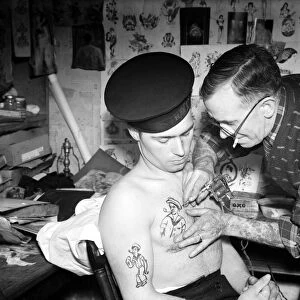 Tattooist applying sailor tattoo to the chest of a sailor on the Royal Navy Circa 1945