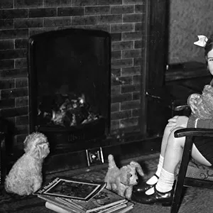 Young girl sitting by fireplace with toy dogs. c. 1945 P044479